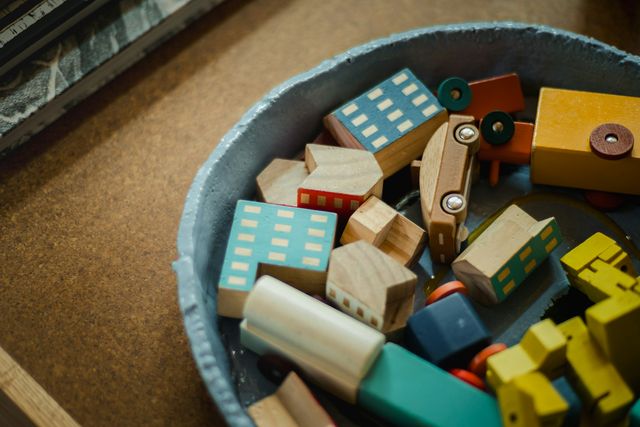 Een mand vol houten blokken in de vorm van huisjes en autootjes