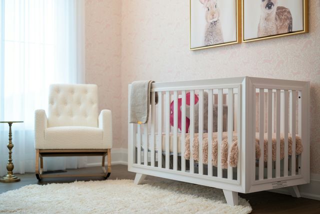 Een wit bedje met een dekentje in een rustige slaapkamer