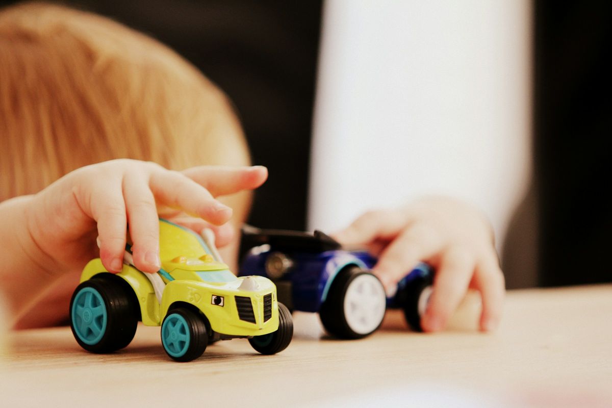 Kinderhandjes spelen met twee speelgoedautootjes op een tafel